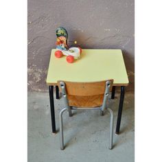 an old school desk with a toy doll sitting on it's top and legs