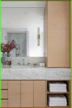 a bathroom with green border around the mirror and sink area, along with folded towels