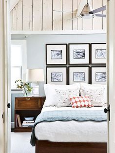 a white bed sitting in a bedroom next to a wooden dresser and window with pictures on the wall