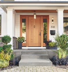 the front door of a house with two planters on either side and steps leading up to it