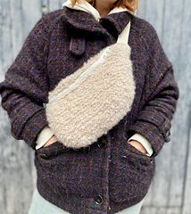 a woman standing in front of a wooden wall wearing a jacket with a hoodie on