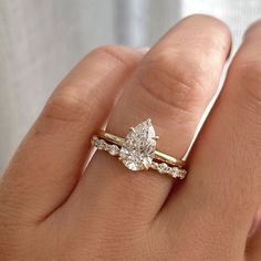 a woman's hand with a diamond ring on top of her finger and the other hand holding an engagement ring