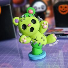 a green toy with pink and purple decorations on it's head sitting on a table