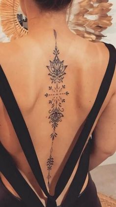 the back of a woman's neck with an intricate tattoo design on her lower back