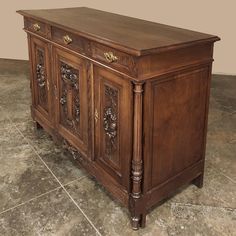 a large wooden cabinet with ornate carvings on the front and sides, sitting on a tile floor