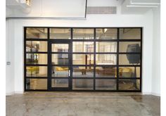 an open garage door with glass panels on the inside and outside, in front of a living room