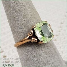 I purchased this vintage ring over 30 years ago at a local antique store that has long since closed. I fell in love with the vintage mounting and the beautiful light green color stone. Unlike most of my rings that I have listed, I actually wore this ring on a somewhat regular basis.  The green stone was listed as peridot. It measures 3/8" x 5/16" and is emerald cut. The band measures 1/16" at bottom and is marked 10k. The ring is size 7 (sorry, when I listed this ring, I listed the size in the i Collectible Green 14k Stamped Jewelry, Heirloom Green Birthstone Ring For May, Heirloom Green May Birthstone Ring, Heirloom Green Emerald Solitaire Ring, Antique Green Ring With 17 Jewels, Vintage Hallmarked Yellow Gold Birthstone Ring, Vintage Yellow Gold Hallmarked Birthstone Ring, Vintage Yellow Gold Gemstone Ring, Vintage Yellow Gold Rings With Gemstones