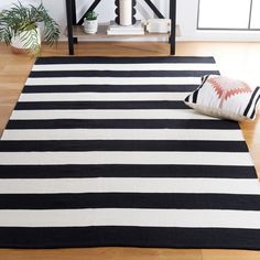 a black and white striped rug with a pillow on the floor in front of it