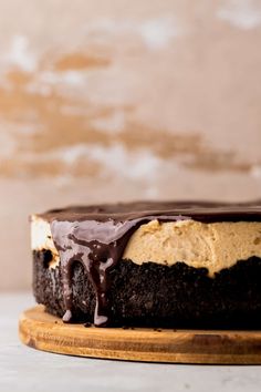 a chocolate cake with peanut butter frosting on a wooden board next to a wall