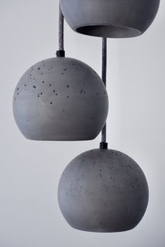 three cement balls hanging from strings in the air