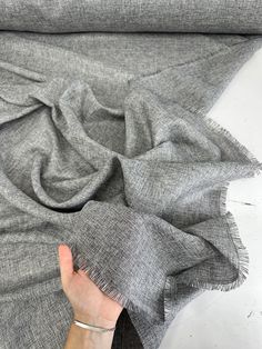 a woman's hand is holding the edge of a gray scarf