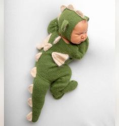 a newborn baby is wearing a green dragon outfit