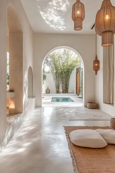 an indoor swimming pool surrounded by white walls and flooring with hanging lights above it