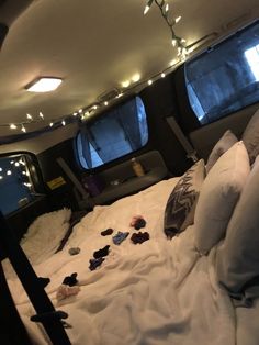 there is a bed with many pillows and lights on the ceiling in front of two windows