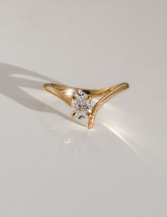 a yellow gold ring with a single diamond in the center on a white table top