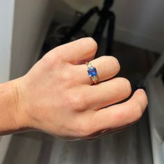 a person's hand with a ring on it and a blue stone in the middle