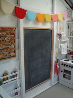 a chalkboard in the corner of a kitchen with an oven, stove and shelves