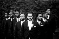 a group of men standing next to each other wearing suits and ties on their heads