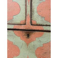 an orange and green painted wooden door with a key hole in the bottom part of it