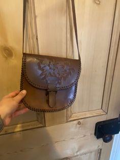 It is a very lovely small vintage bag. It has a leather strap that goes across the body and has an adjustable buckle on it.  There is a pretty floral design on the main body of the bag and it has buckle and the magnetic clasp as a fastening.  I'm not hundred percent sure that the main body of the bag is leather. It looks leather by there is something not quite right. Maybe it's a different quality or a very good imitation. The strap is definitely a leather. It's super useful and will work great at the festival or a gig. Vintage Crossbody Satchel For Daily Use, Vintage Crossbody Satchel With Detachable Strap, Vintage Saddle Bag With Detachable Strap For Daily Use, Vintage Satchel Shoulder Bag With Detachable Strap, Vintage Brown Bag With Adjustable Strap, Vintage Crossbody Satchel, Vintage Satchel Saddle Bag With Adjustable Strap, Vintage Brown Satchel Shoulder Bag, Vintage Saddle Bag With Detachable Strap