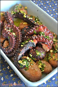 an octopus dish in a white bowl on a blue tablecloth with yellow sprinkles