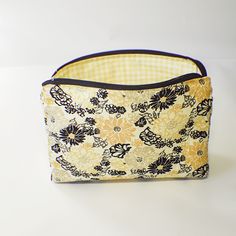 a yellow and black flowered bag sitting on top of a white table