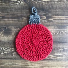 a crocheted red ornament with an elephant on it sitting on a wooden surface