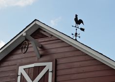 a rooster weather vane on top of a red barn