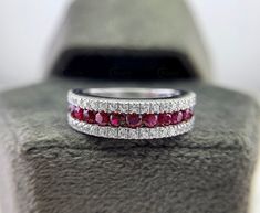 a wedding band with three rows of red and white diamonds on top of a table