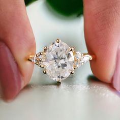 a woman's hand holding an engagement ring with a diamond in the middle and three stones on each side