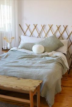 a bed with two pillows on top of it next to a wooden table and window