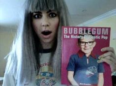 a woman with grey hair holding up a magazine