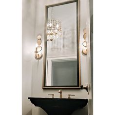 a bathroom with a sink, mirror and lights on the wall above it is shown