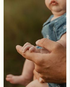 a man holding a baby in his arms with both hands on the other side of him