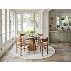 a dining room table with four chairs and a round rug in front of the door