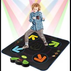 a young boy standing on top of a black mat covered in colorful sticker art