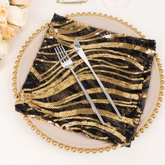 a plate topped with a fork and knife next to a napkin covered in gold sequins