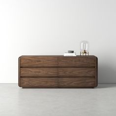 a wooden dresser sitting on top of a white floor next to a wall with a clock