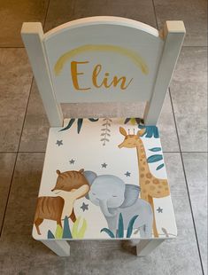 a child's wooden chair with an elephant and giraffe design on it