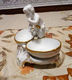 there is a small figurine sitting on top of a saucer and bowl