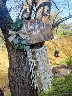 a wooden sign that says charlotte genee hanging from a tree in front of a fence