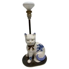 a white cat figurine sitting next to a lamp