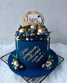 a blue and gold birthday cake with decorations on the top is sitting on a wire rack