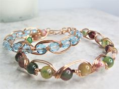 a close up of a bracelet on a marble surface with beads and wire work around it