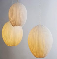 two white lamps hanging from strings on a gray background