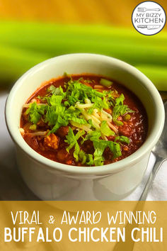 a white bowl filled with chili and green garnish