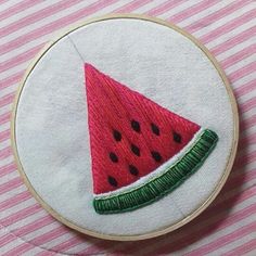 a watermelon slice embroidered on a white hoop with pink and white striped tablecloth