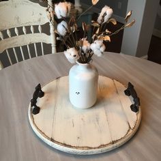 a white vase filled with flowers on top of a wooden table