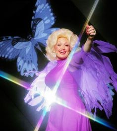 a woman dressed in purple holding a butterfly wand