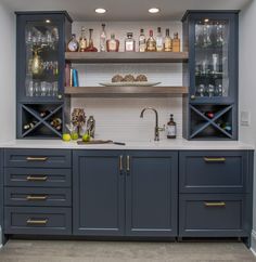 a kitchen with blue cabinets and shelves filled with liquor bottles on top of counter tops